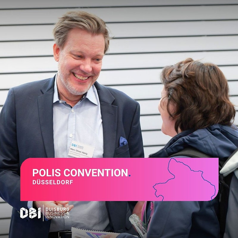 Auf der POLIS-Tagung in Düsseldorf stehen zwei Personen und lächeln einander an. Beide tragen Business-Kleidung und Namensschilder. Am unteren Bildrand ist ein rosa Banner mit Veranstaltungsdetails und einem Kartenausschnitt zu sehen.